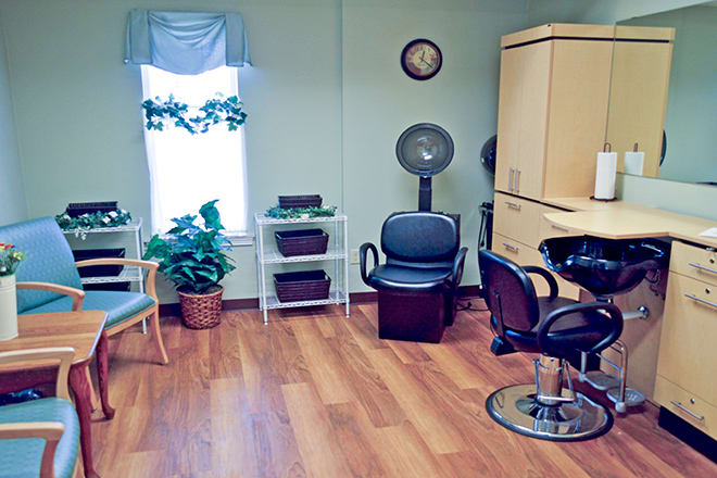 A cozy hair salon with chairs, a hair dryer, and potted plants.