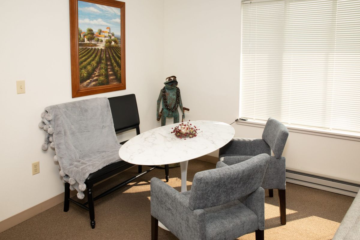 A cozy office meeting area with a round table, chairs, and decorative items.