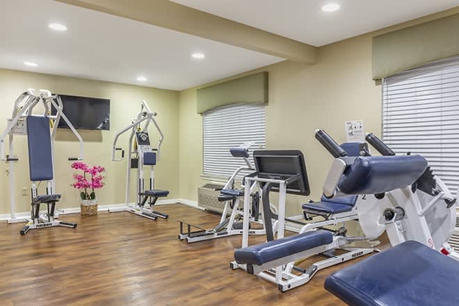 A well-equipped gym with various exercise machines and wooden flooring.