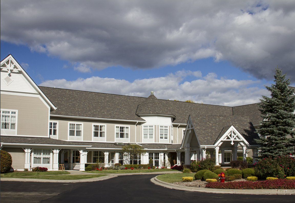 A large building with a landscaped front yard under a cloudy sky.