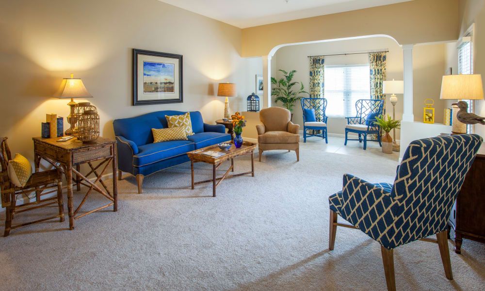 A cozy living room with a blue sofa, armchairs, and elegant decor.