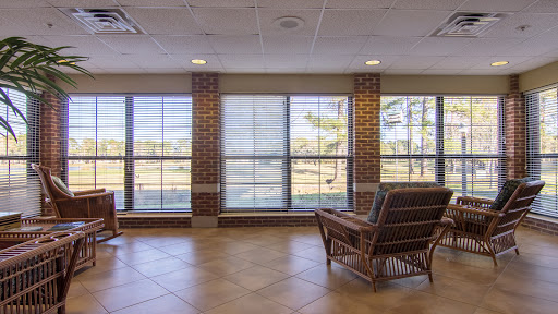 A serene lobby area featuring large windows that invite natural light, complemented by a stylish seating arrangement against a brick wall.