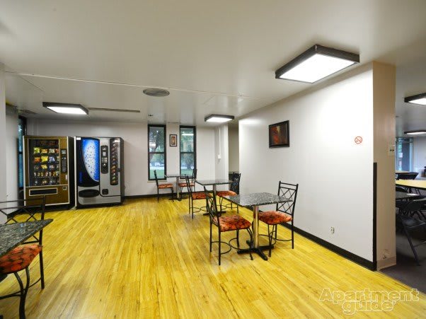 A break room with vending machines, tables, and chairs on a wooden floor.