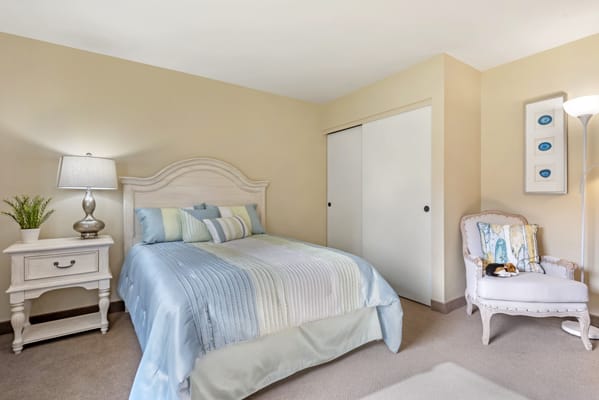 A cozy bedroom with a neatly made bed and pastel-colored decor.