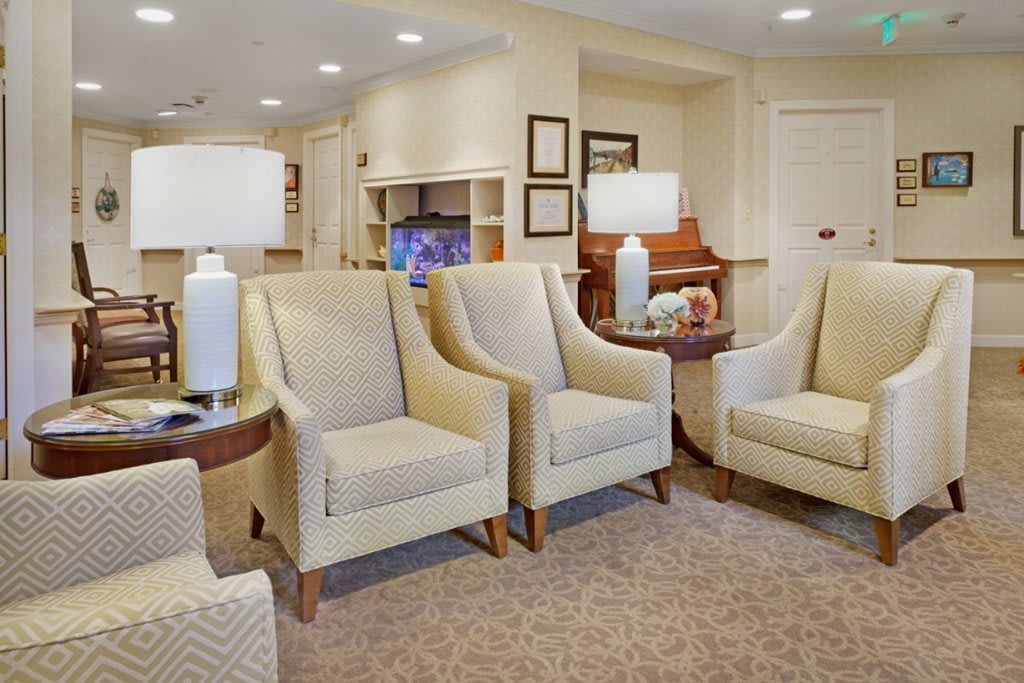 A cozy living room with beige chairs, a sofa, table, and lamps.