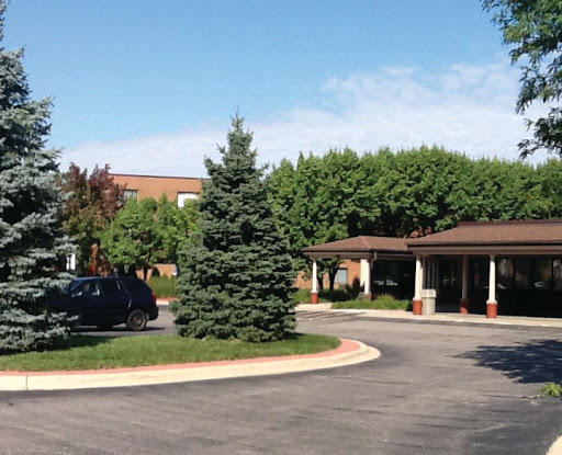 A welcoming entrance with lush greenery and a circular driveway.