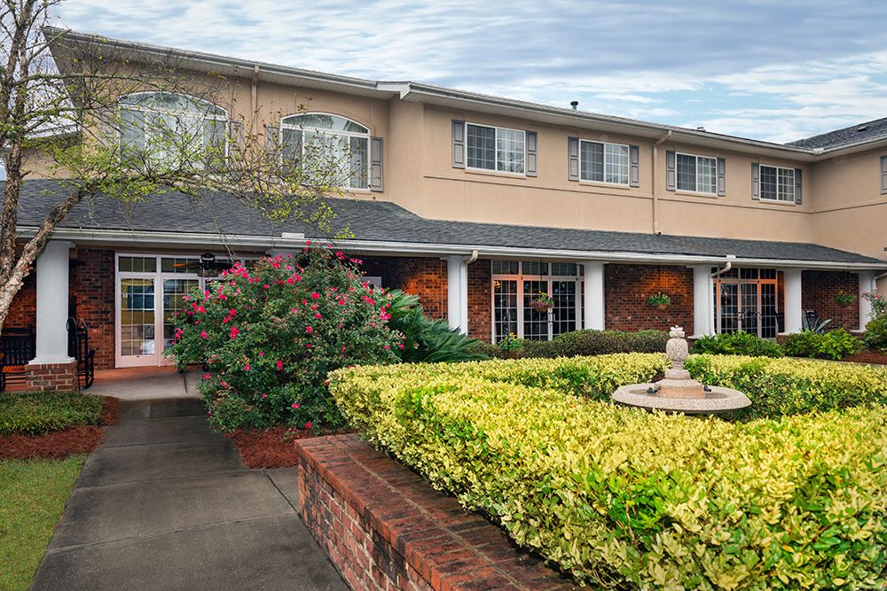 A two-story building with a well-maintained garden and a fountain at the entrance.