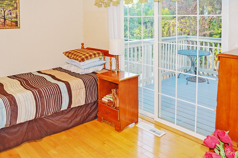A cozy bedroom with a bed, nightstand, and a sliding glass door leading to a balcony.