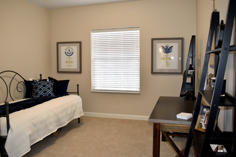 A cozy bedroom with a bed, desk, and framed artwork on the walls.
