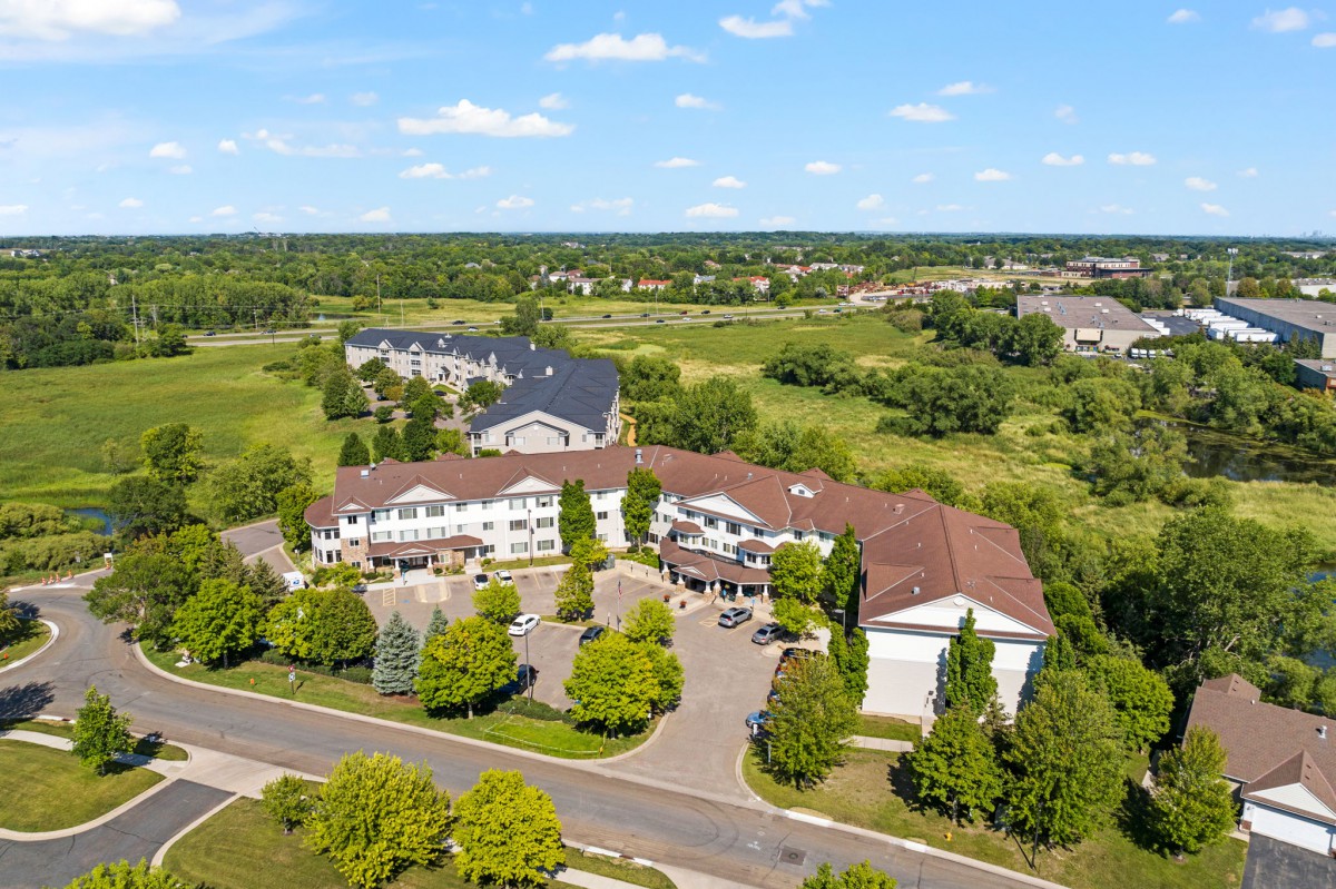 An aerial view of a residential complex surrounded by greenery and open fields.