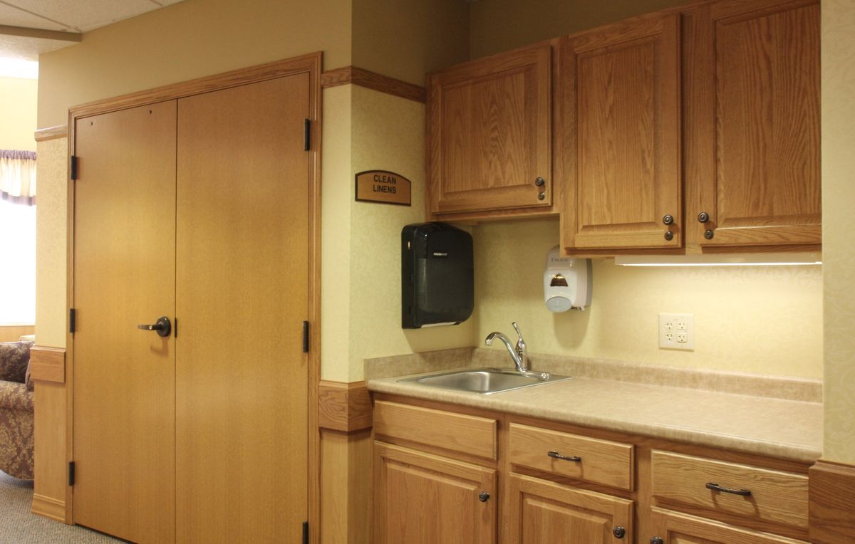 A small kitchen area with wooden cabinets, a sink, and a closed door.