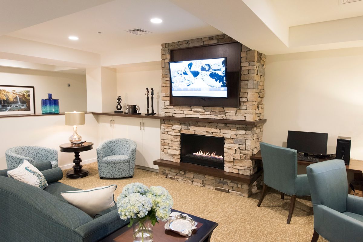 A cozy living room with a stone fireplace and modern seating, complemented by a mounted television.