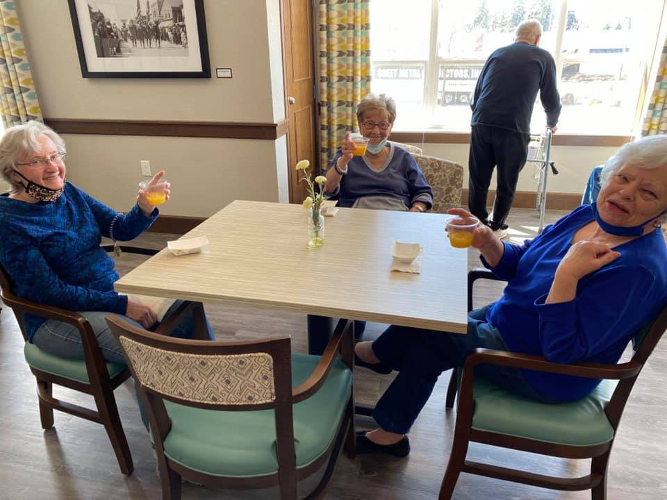 A group of seniors enjoying drinks and conversation at a table in a community setting.