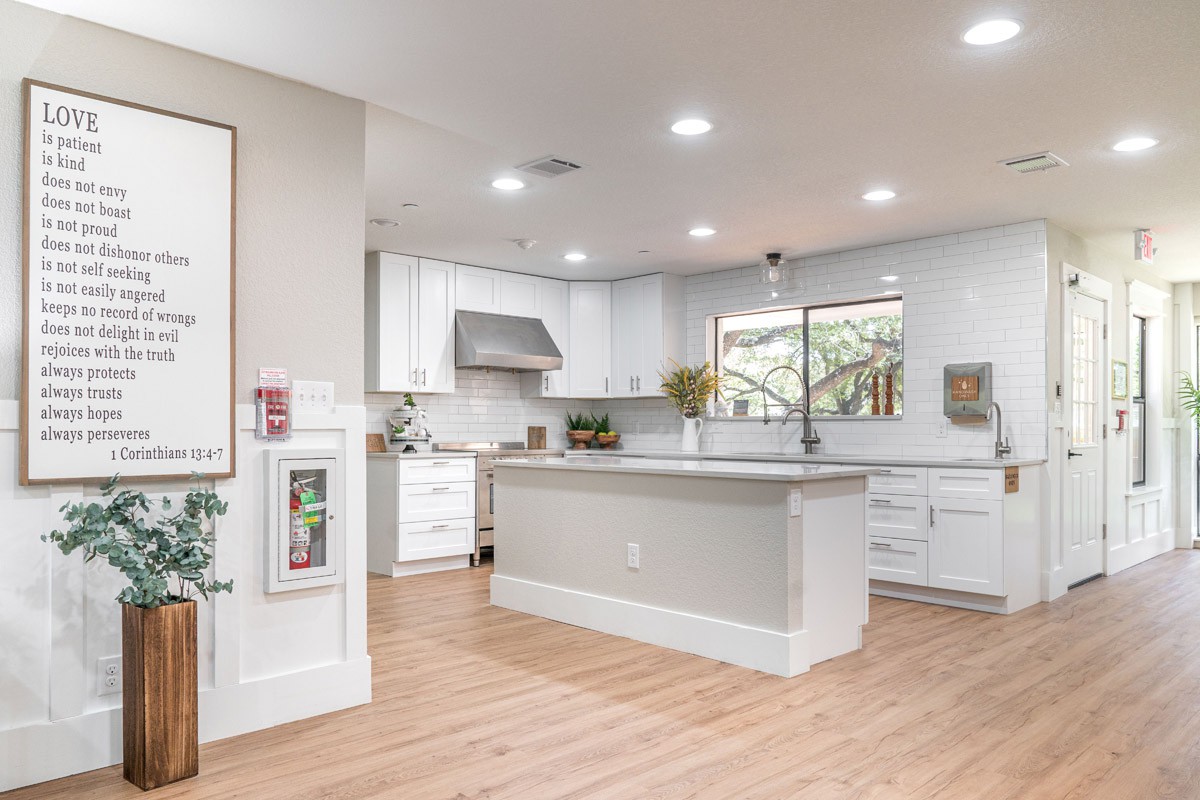 A modern kitchen featuring white cabinets, a central island, and stainless steel appliances, with ample natural light.