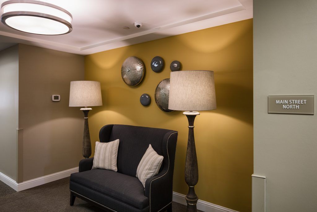 A cozy living room corner with a dark sofa, floor lamps, and circular wall decor.