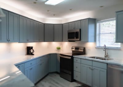 A modern kitchen with blue cabinetry and stainless steel appliances.