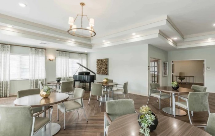 A spacious dining area featuring a grand piano, modern tables and chairs, with elegant lighting and decor.