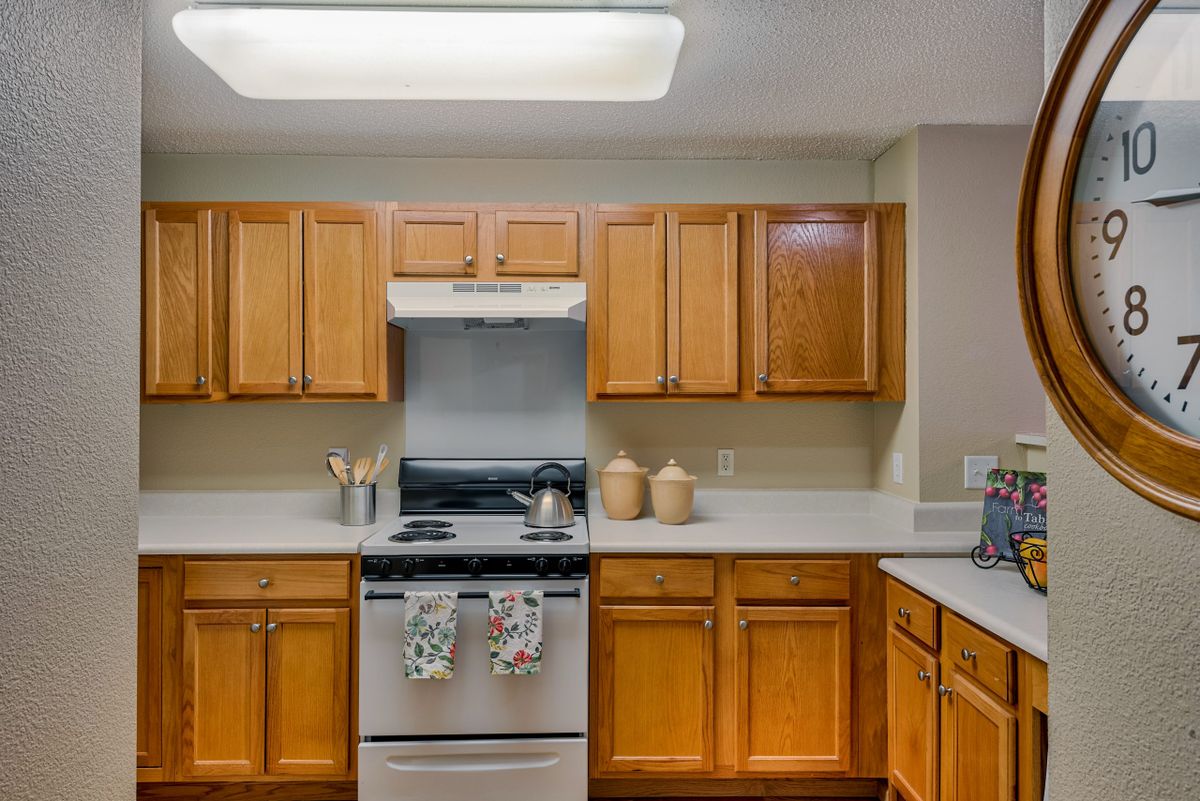 A kitchen with wooden cabinets, a stove, and various appliances.