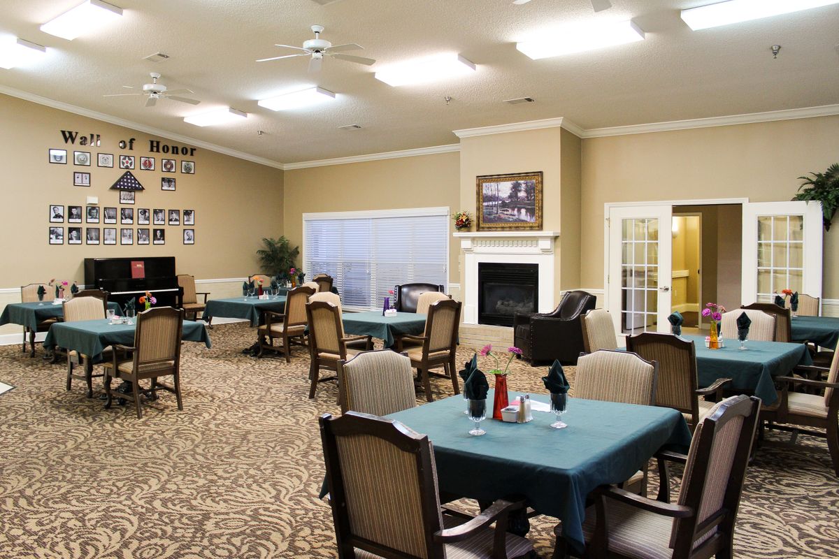 A well-lit dining area with multiple tables and chairs, featuring a fireplace and decorated walls.