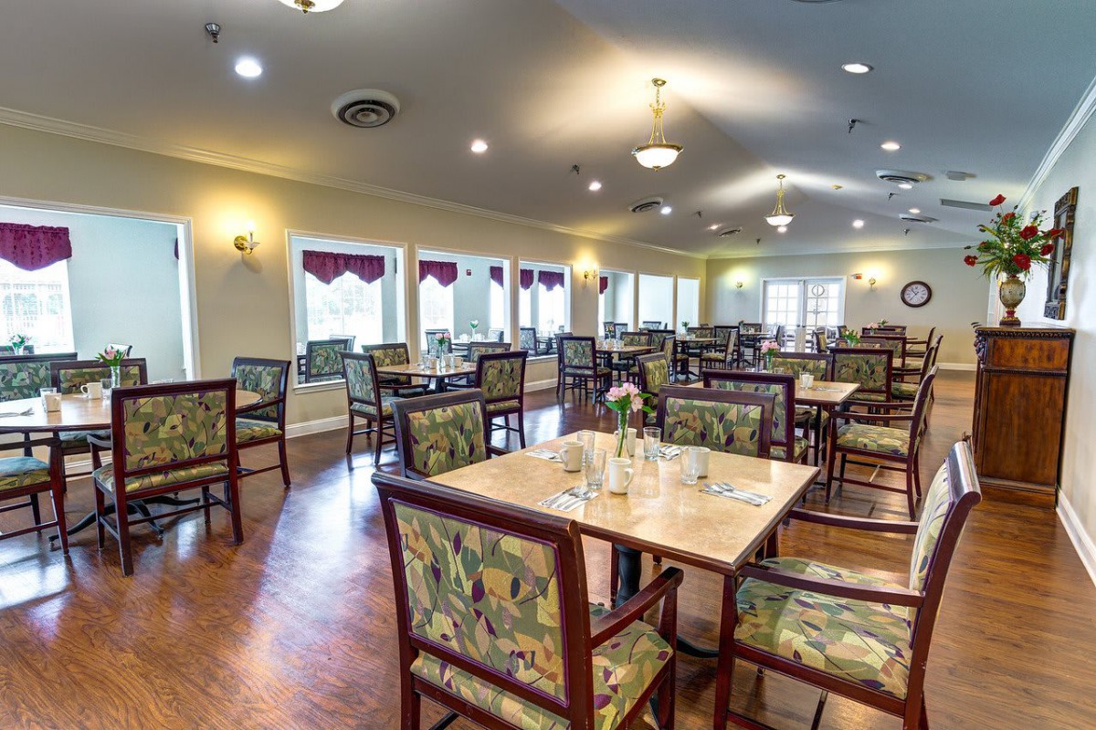 An empty dining hall with neatly arranged tables and chairs.