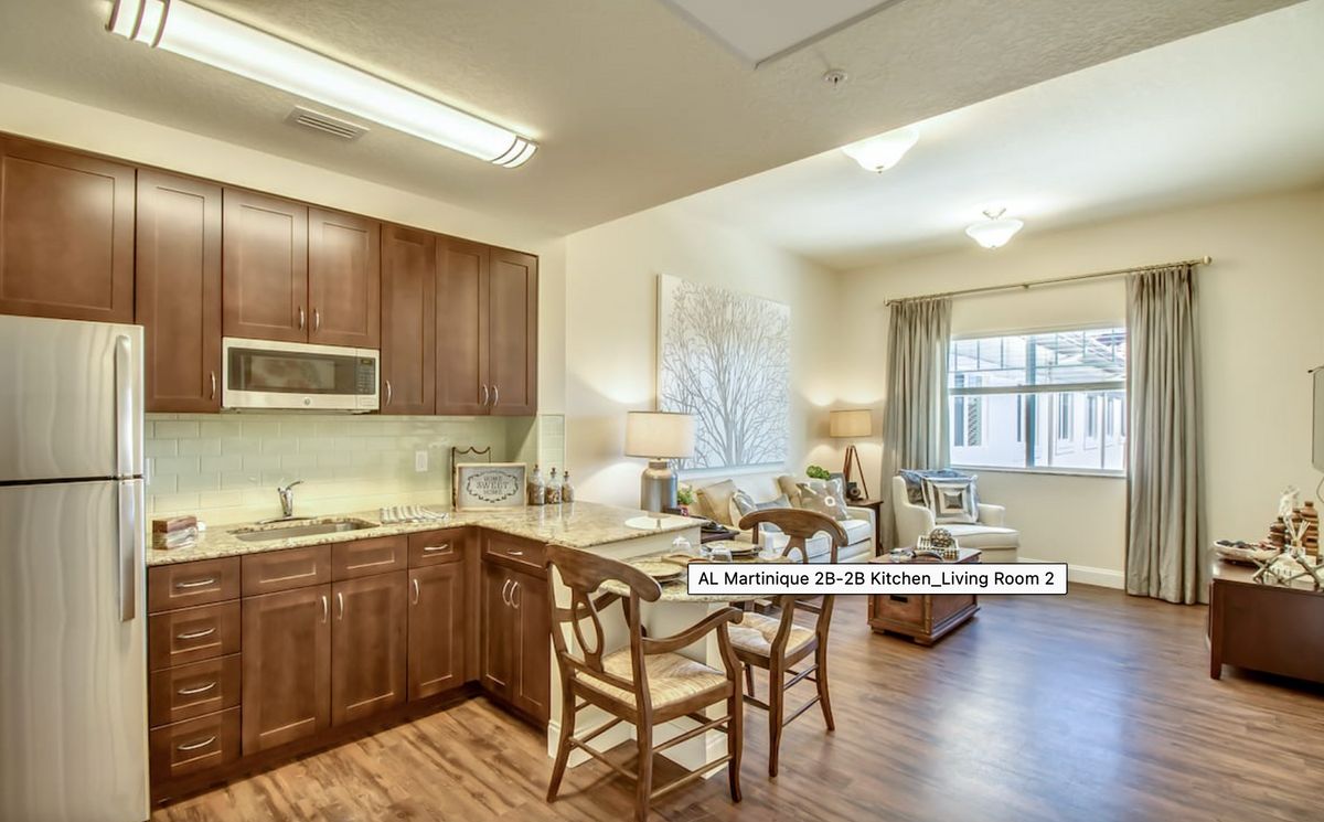 A modern apartment featuring an open kitchen and living room with wooden flooring and bright lighting.