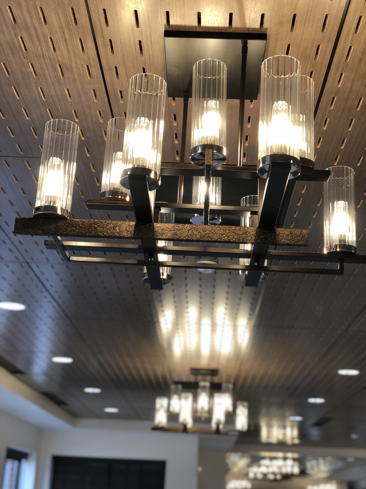 A modern chandelier with multiple cylindrical glass lights illuminating an indoor space.