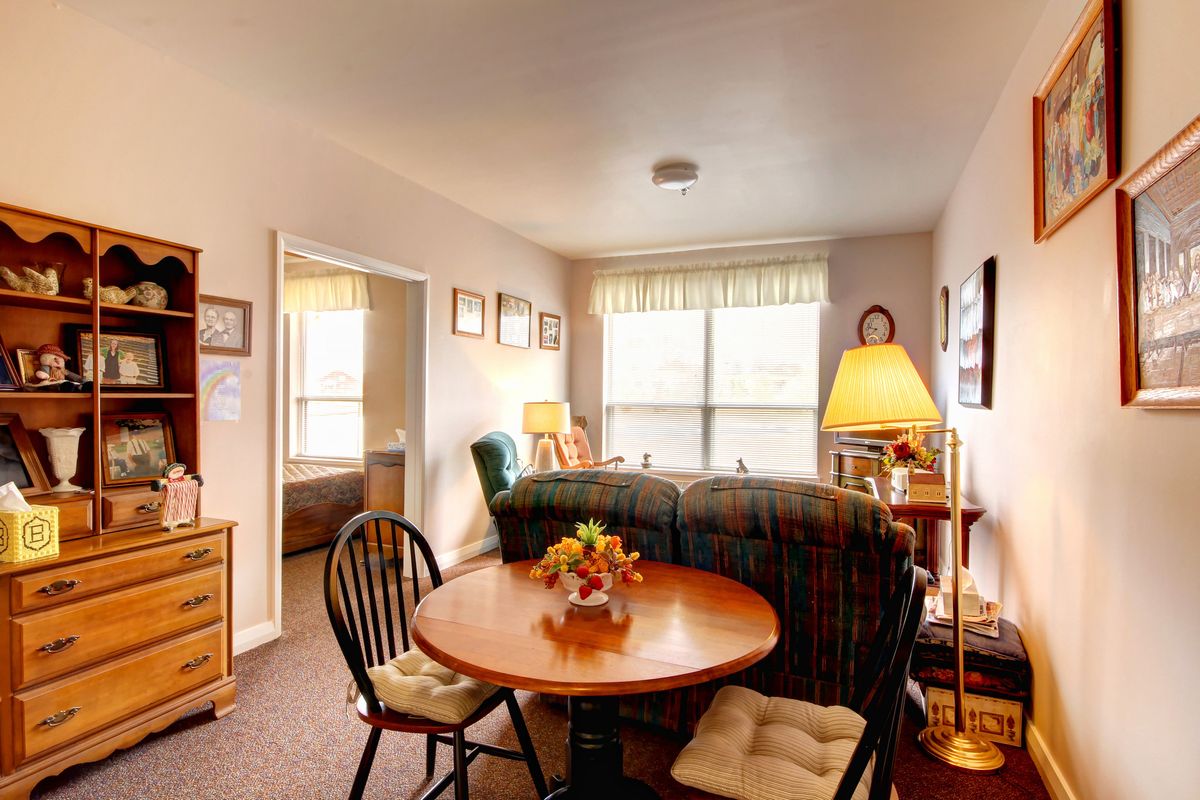 A cozy living room with a small dining area, featuring comfortable furniture and warm lighting.