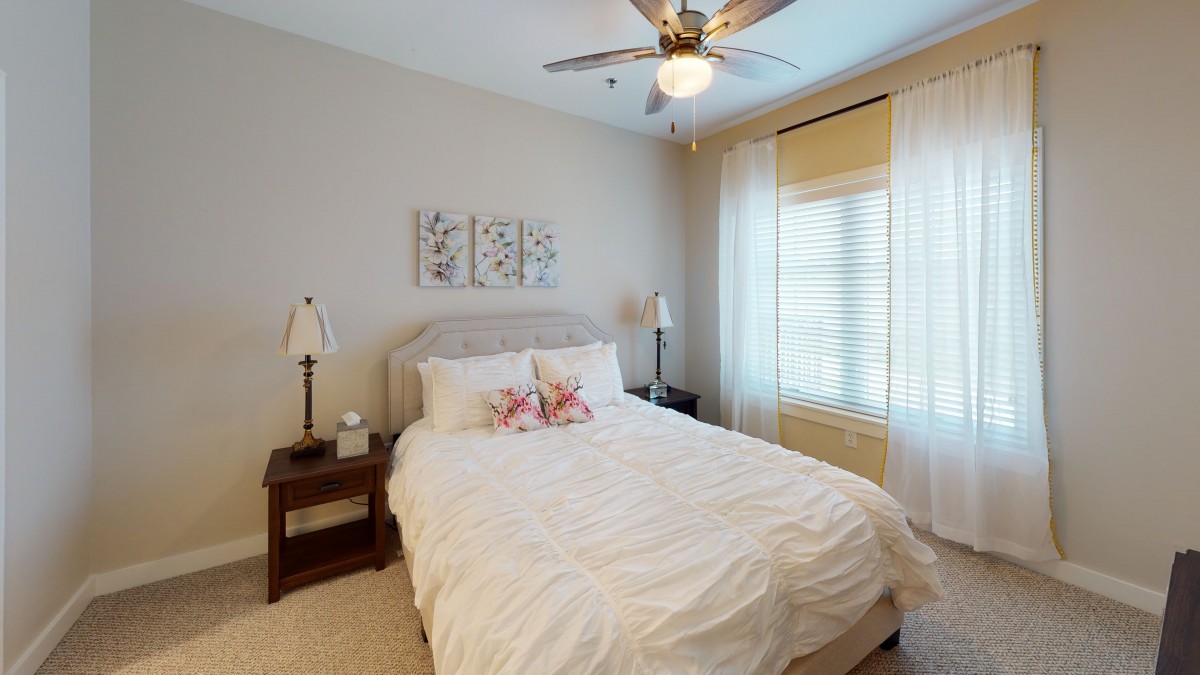 A cozy bedroom featuring a neatly made bed, decorative pillows, and elegant curtains.