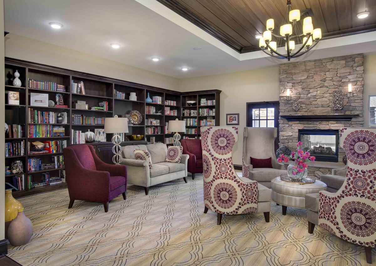 A cozy living room with bookshelves and comfortable seating arranged around a fireplace.