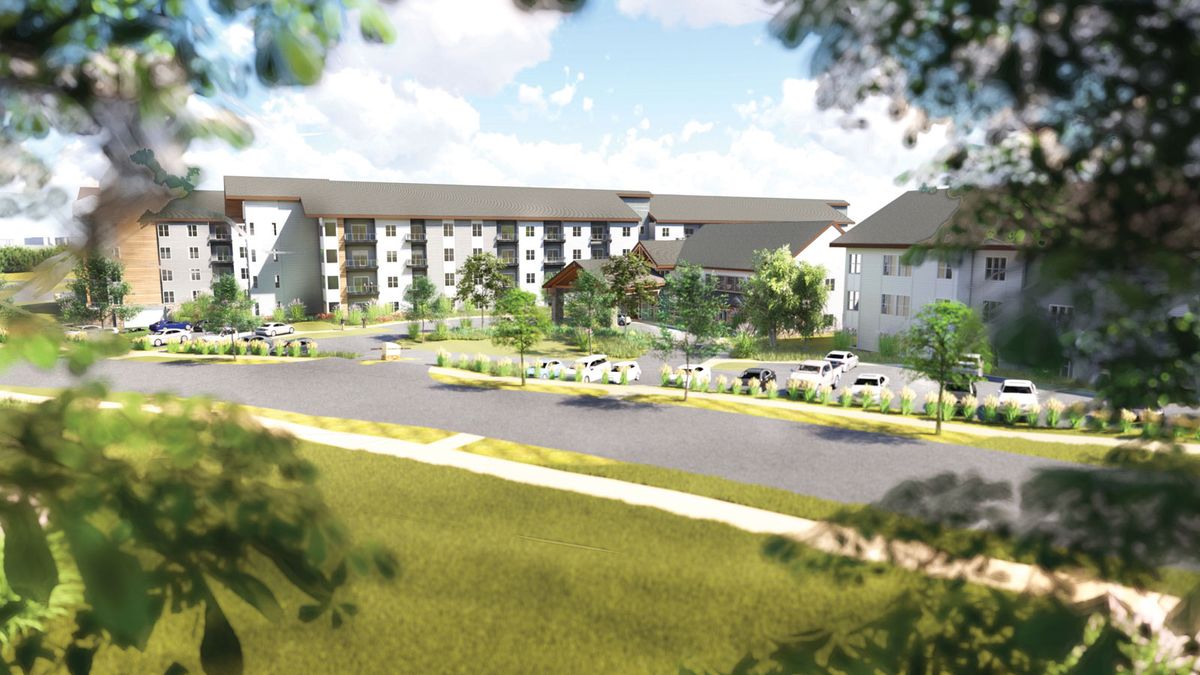 A serene view of a modern apartment complex surrounded by lush greenery and a spacious parking area.