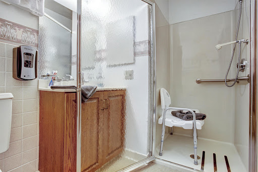 A spacious and modern bathroom featuring a shower, vanity sink, and accessible seating.