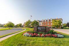 A view of Independence Village retirement community, featuring a well-maintained lawn and colorful flower beds with a clear sky in the background.