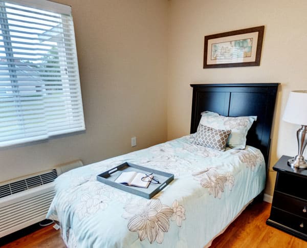 A cozy bedroom with a single bed featuring a decorative pillow and artwork on the wall.