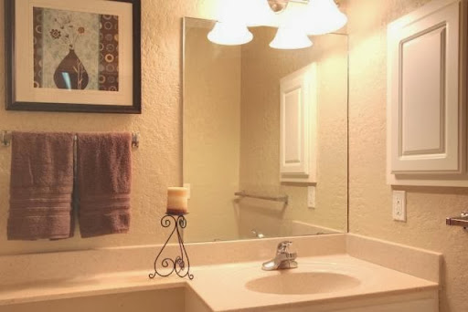 A well-lit bathroom featuring a sink, mirror, decorative candle, and towel.