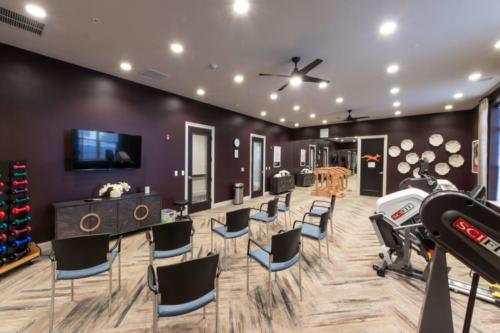 A modern meeting room with chairs arranged for a conference, featuring a television and sleek decor.
