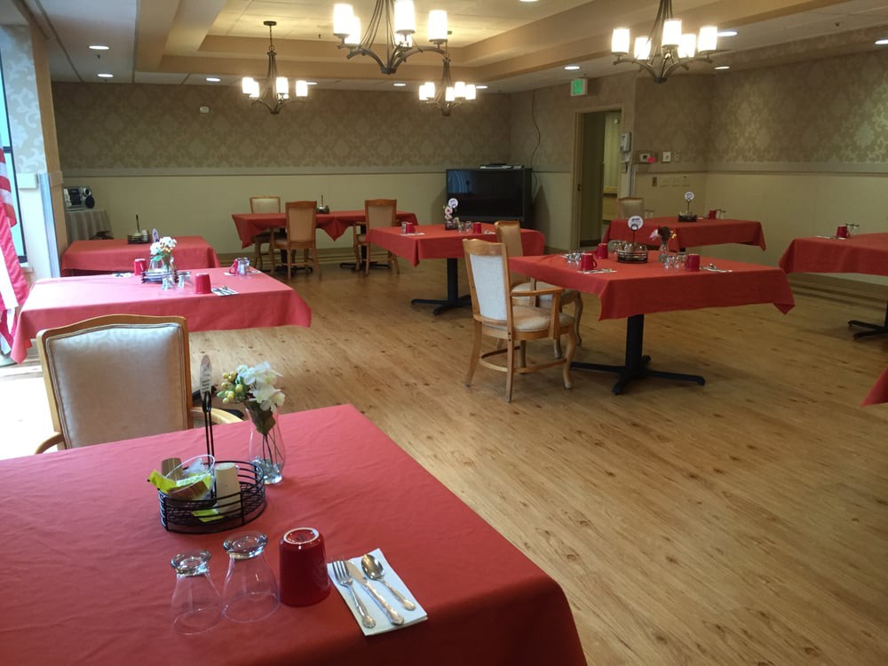 A restaurant dining area with red tablecloths and chandeliers.