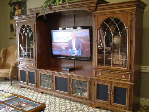 A spacious wooden entertainment center featuring a television and glass-front cabinets.
