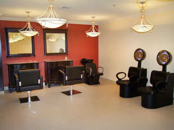 A modern salon interior featuring elegant chandeliers, mirrors, and comfortable seating arrangements.
