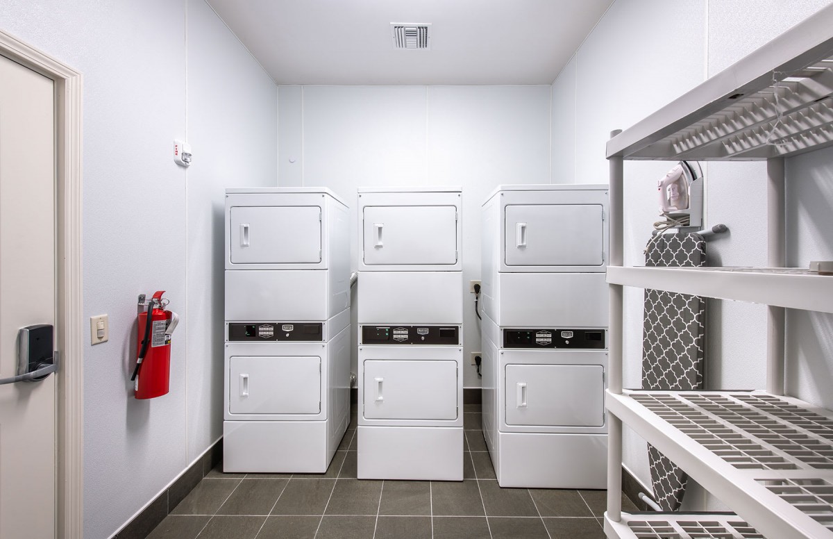 A clean laundry room with stacked washers and dryers.