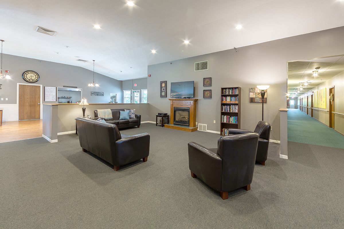 A spacious living room with modern furniture, featuring a fireplace and ample lighting.