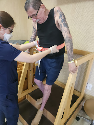 A healthcare professional assists a patient in a rehabilitation setting.