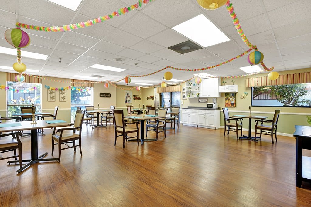 A decorated community dining room with tables and chairs arranged neatly.