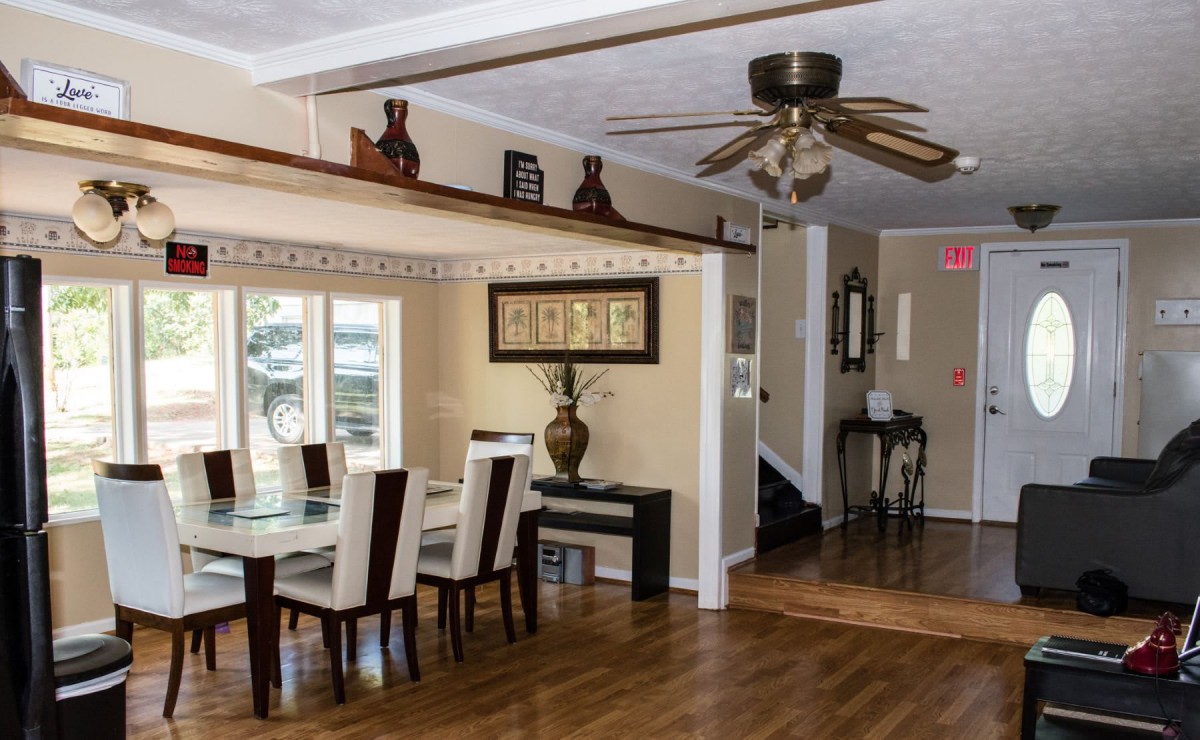A stylish dining room with a wooden floor, elegant dining table, and ceiling fan.