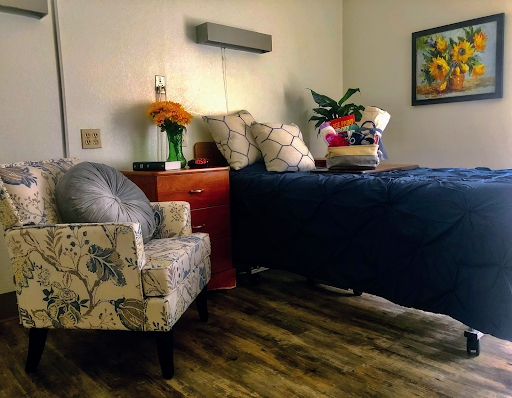 A cozy and inviting bedroom setup with a comfortable bed, decorative chair, and vibrant plants.