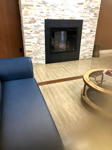 A cozy living room featuring a blue couch, round coffee table, and a modern stone fireplace.