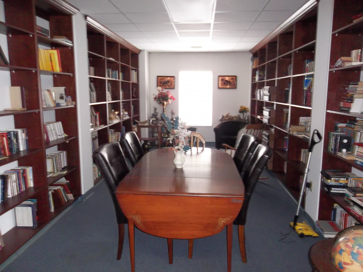 A library-like meeting room with a wooden conference table surrounded by chairs and lined with bookshelves.