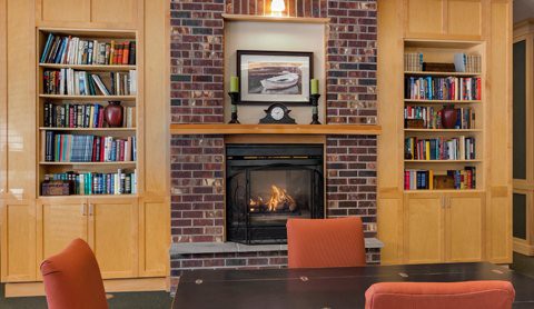 A cozy living room with a brick fireplace and built-in bookshelves.