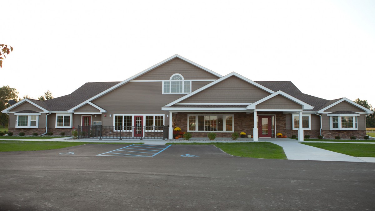 A symmetrical residential building with a driveway and parking spaces in front.