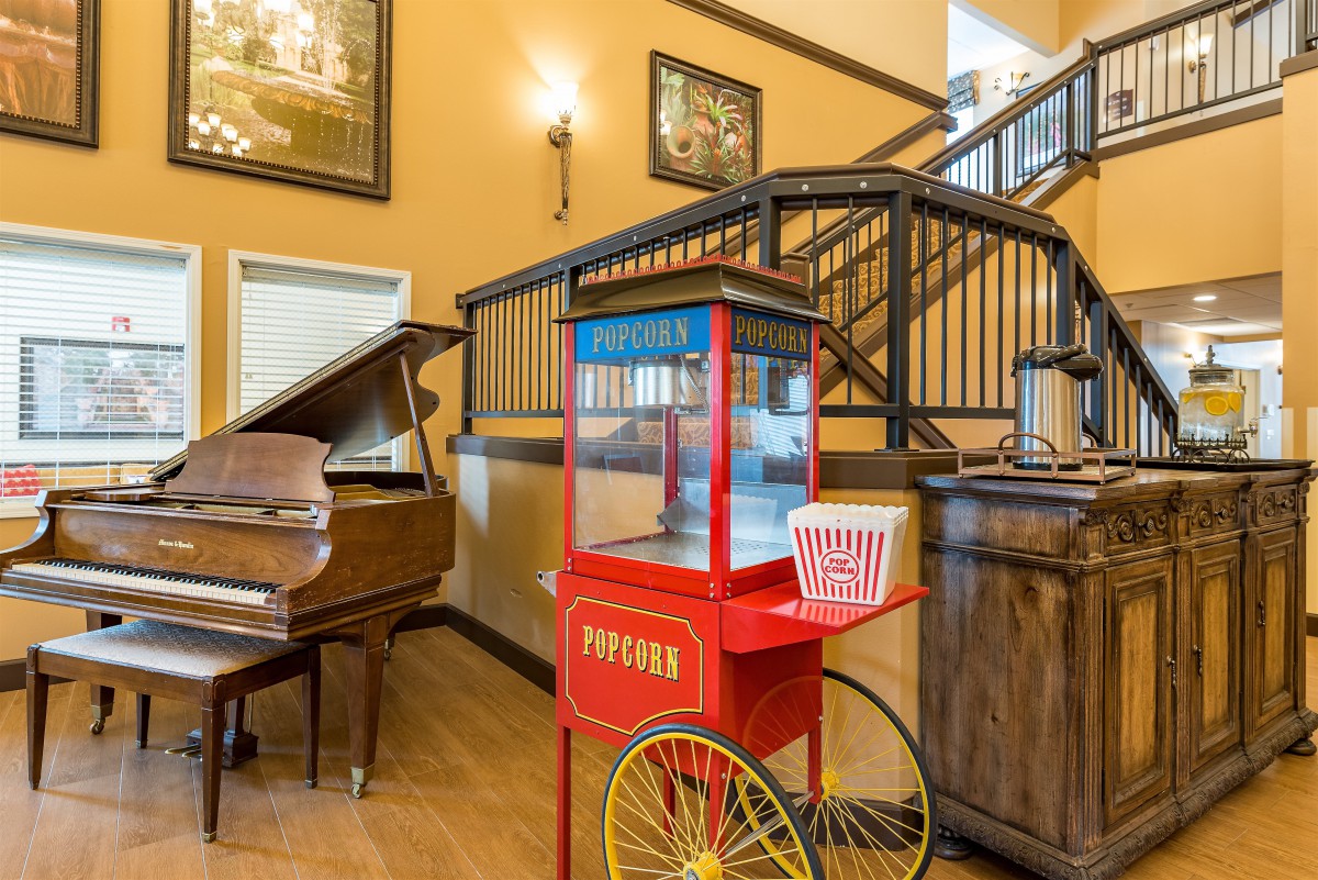 A cozy interior featuring a vintage popcorn machine and a grand piano beside an elegant staircase.