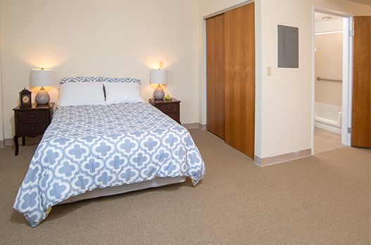 A cozy bedroom with a bed, nightstand, and a closet.
